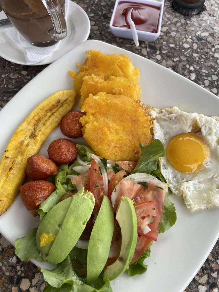 Bord met Ecuadoraanse llapingachos met spiegelei, avocado, salade, worst en banaan, geserveerd tijdens een Galápagos-cruise met ons bureau