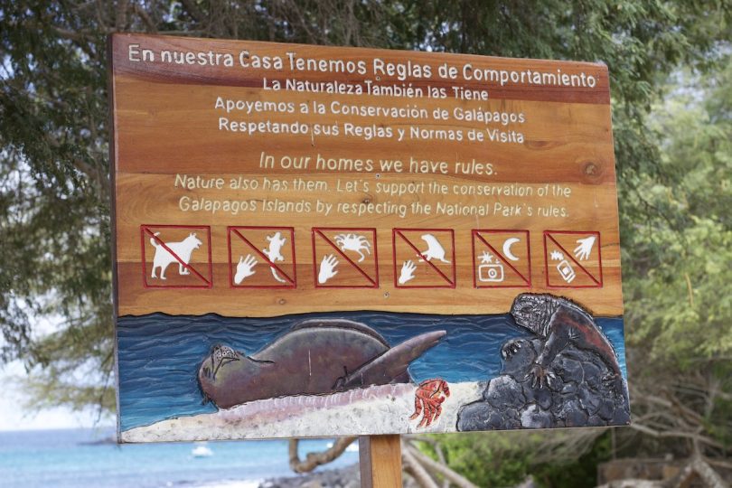 Schild mit den Besucherregeln des Galápagos-Nationalparks und Symbolen, die Reisende daran erinnern, Wildtiere während einer Kreuzfahrt nicht zu berühren, zu füttern oder zu stören